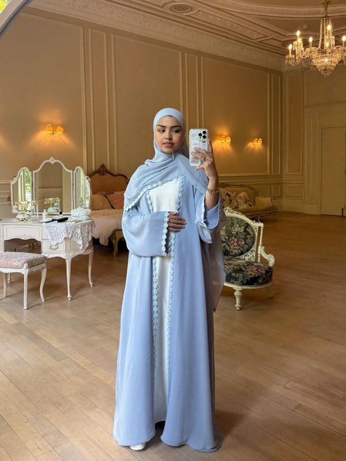 Femme portant l'Abaya Horizon bleu pastel ornée de dentelle, coupe oversize pour un style élégant et modeste.