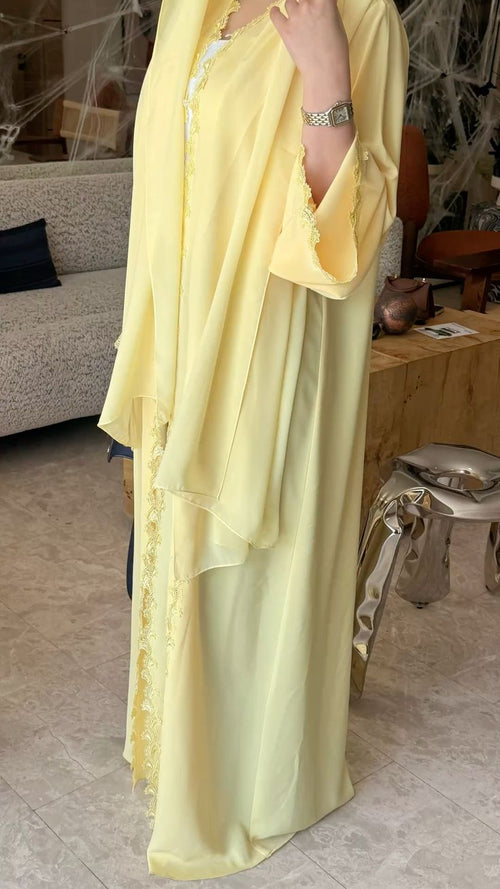 Détails de l'Abaya Solaire jaune pastel avec finitions en dentelle, une robe ample et fluide au look chic.