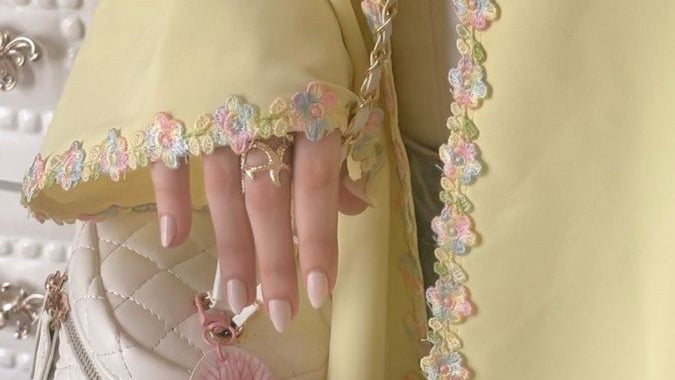Abaya Solaire de Hinari Couture : une abaya jaune pastel ornée d'une bordure en dentelle fleurie multicolore, coupe fluide et élégante pour la mode modeste.
